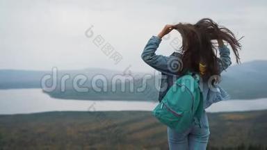 美丽的女人<strong>站在山顶</strong>上，长长的头发随风飘扬，微笑着试图保住她的头发